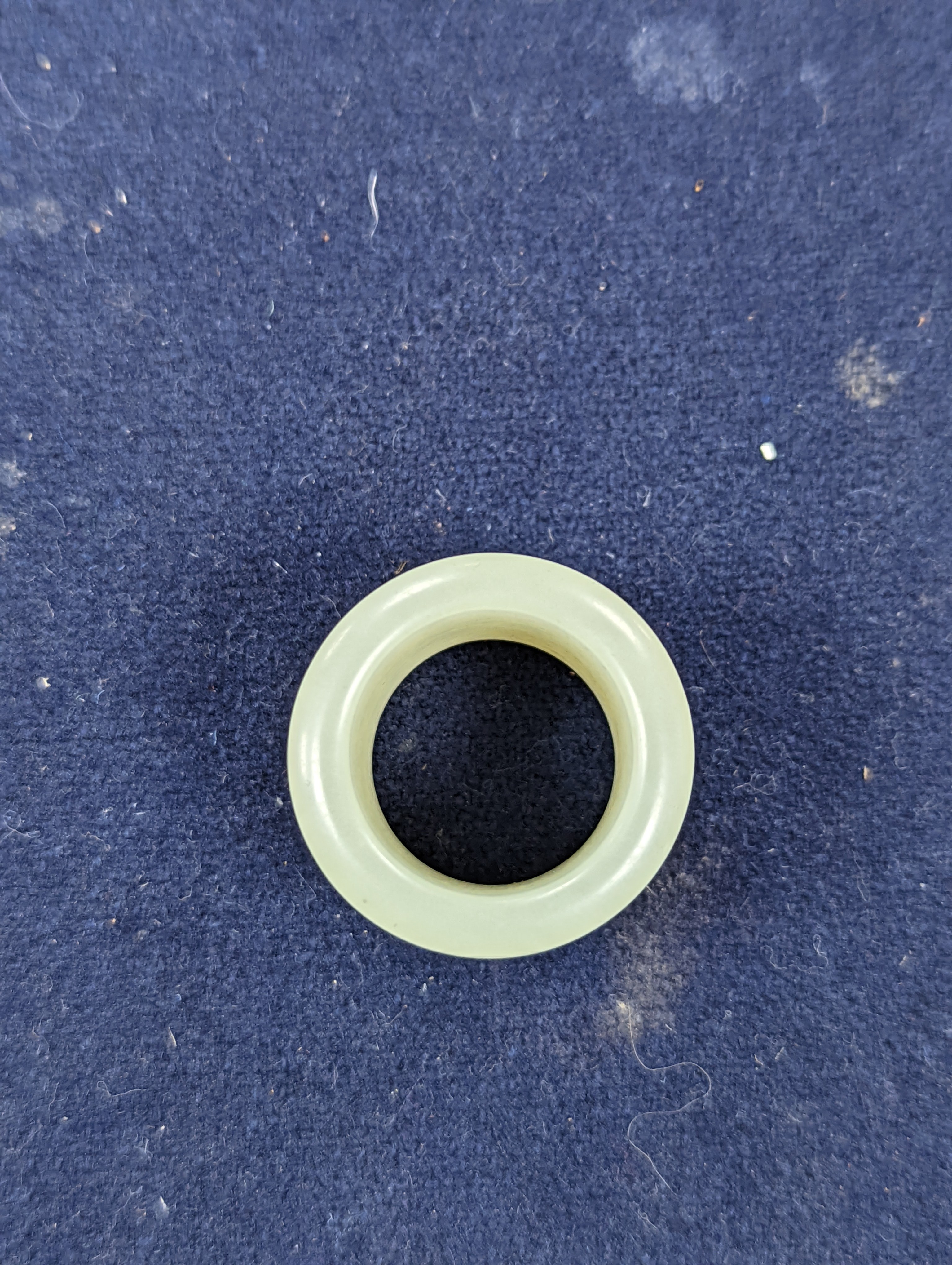 A 19th century Chinese pale celadon jade archer’s thumb ring, inscribed, 3 cm diameter